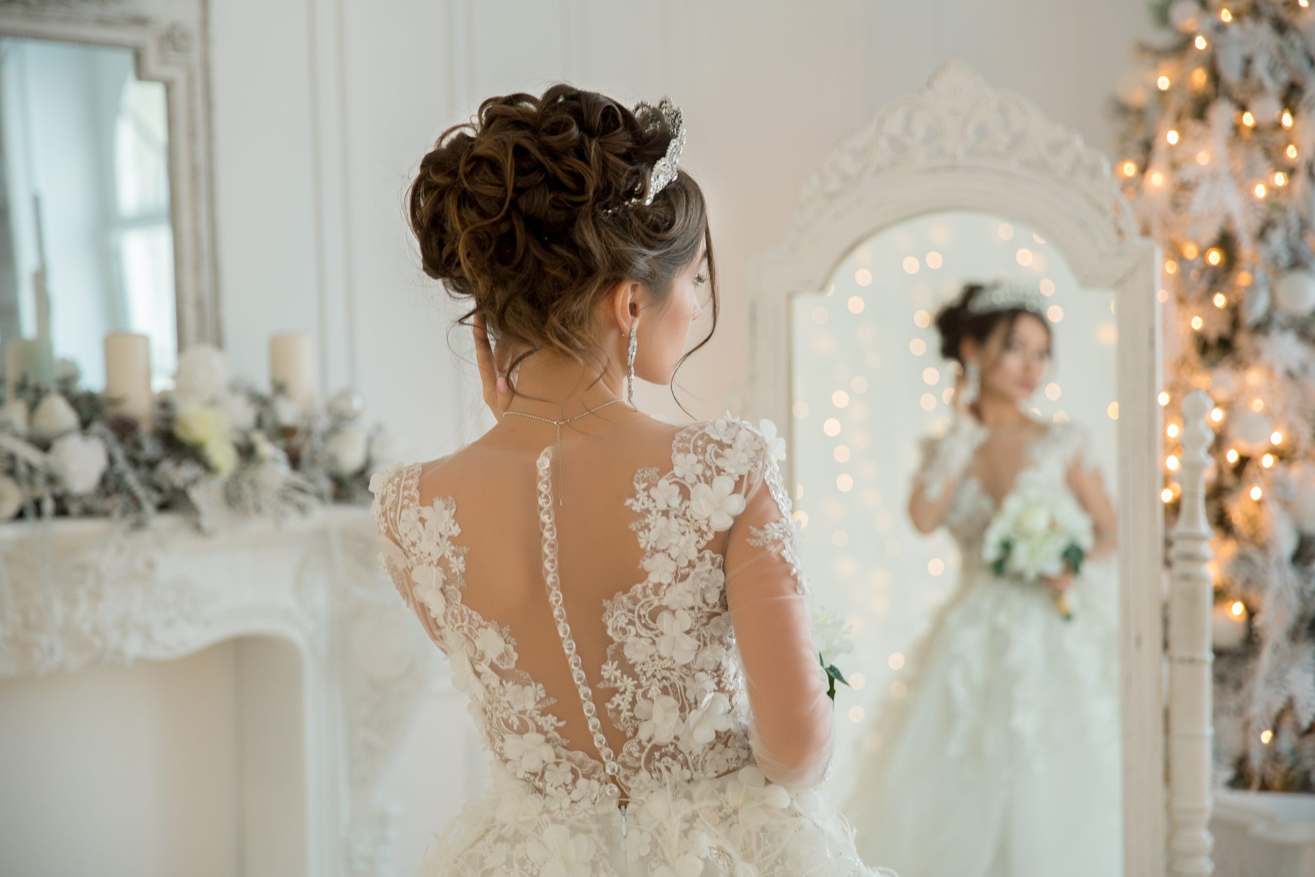 Beautiful bride in a wedding dress at a mirror in Christmas. Gir